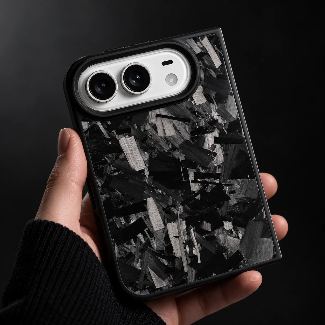 DUO forged carbon case held in hand in a dark setting